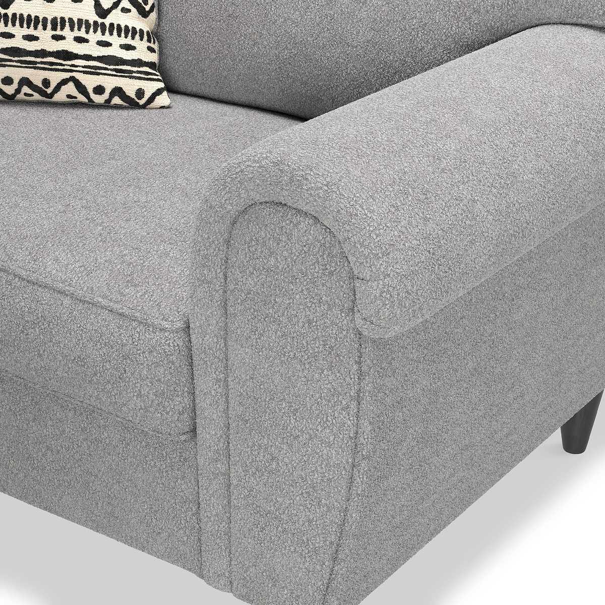 A grey fabric sofa arm, with a patterned cushion resting against its backrest.