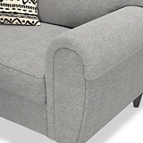 A grey fabric sofa arm, with a patterned cushion resting against its backrest.