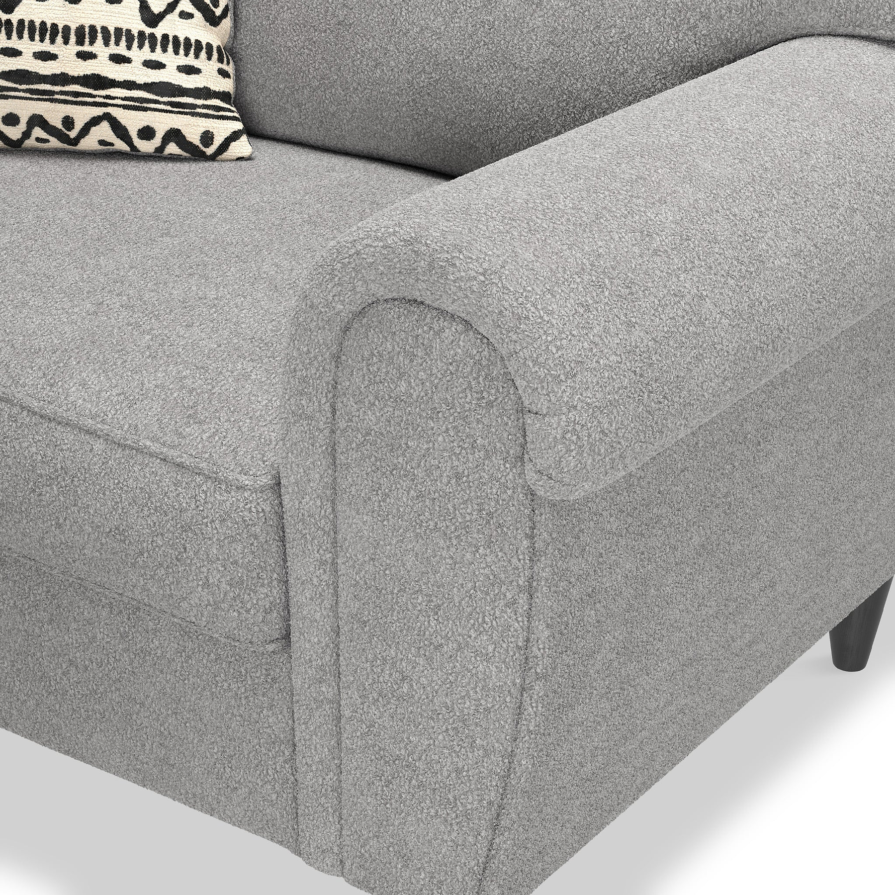 A grey fabric sofa arm, with a patterned cushion resting against its backrest.