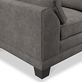 A section of a grey fabric sofa with a cushion and a visible armrest, set against a plain, light background.
