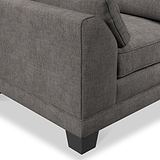 A section of a grey fabric sofa with a cushion and a visible armrest, set against a plain, light background.