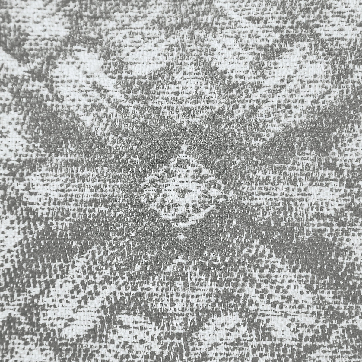 A textured pattern with a symmetrical, ornate central motif contrasting with the surrounding rough surface.