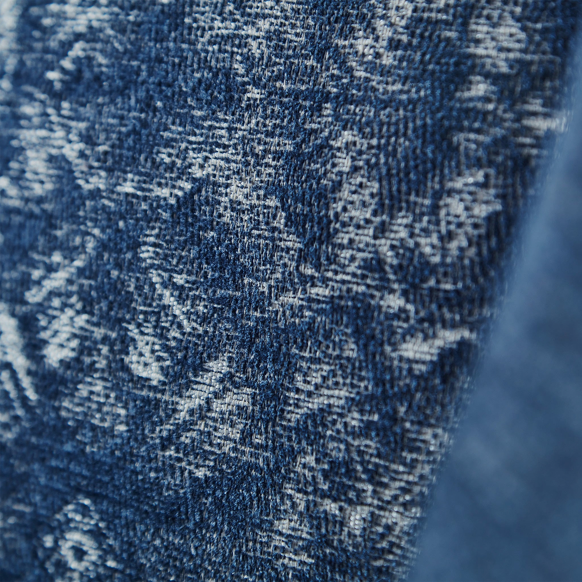 A close-up of denim fabric textures with contrasting shades of blue and white threading, highlighting the material's weave and rugged quality.