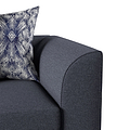 A patterned pillow rests on a dark gray sofa, with a focus on the armrest and cushion.