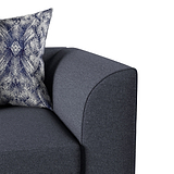 A patterned pillow rests on a dark gray sofa, with a focus on the armrest and cushion.
