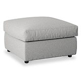 A light gray upholstered ottoman sits idly against a pure white background, featuring a tufted cushion top and short dark legs.