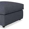 A dark grey ottoman on a white background, featuring a fabric texture and visible black feet.