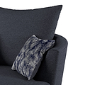 A dark gray upholstered armchair with a patterned blue and white throw pillow angled casually on the seat. The background is a neutral light gray.