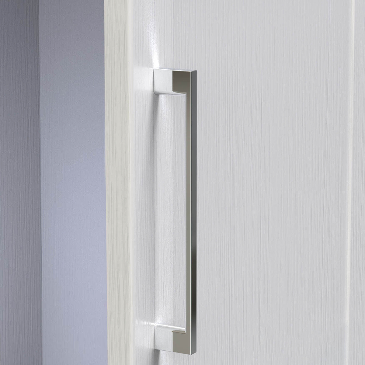 A silver, vertical door handle on a white textured door, partially opened against a light grey wall, indoor setting, with light shadowing.
