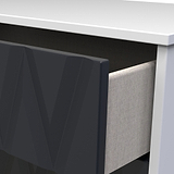 A close-up of a partially open dark drawer under a white tabletop, showing a glimpse of a light-textured object inside.