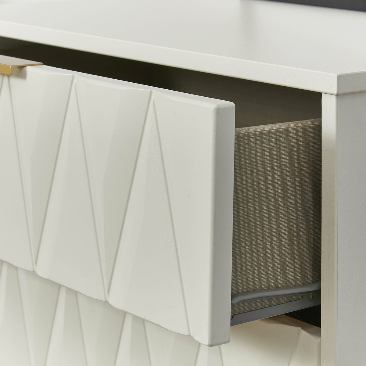 A white drawer with a geometric pattern is partially open, revealing a grey fabric interior with an item inside, against a white background.