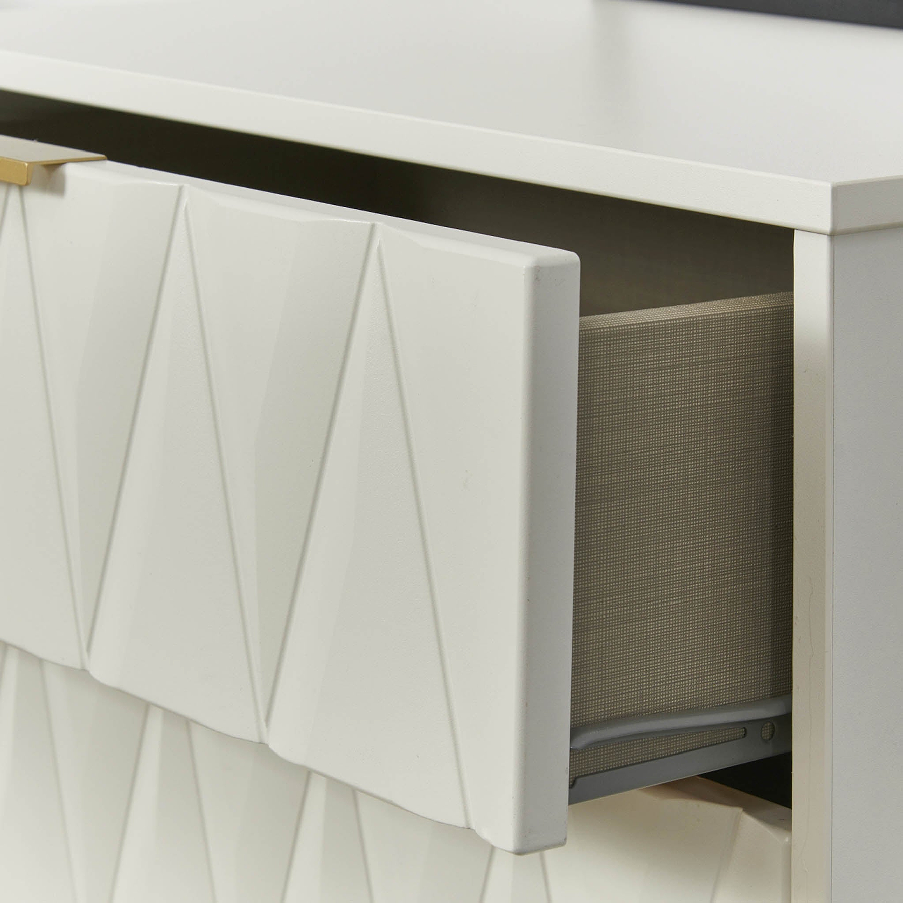 A white drawer with a geometric pattern is partially open, revealing a grey fabric interior with an item inside, against a white background.