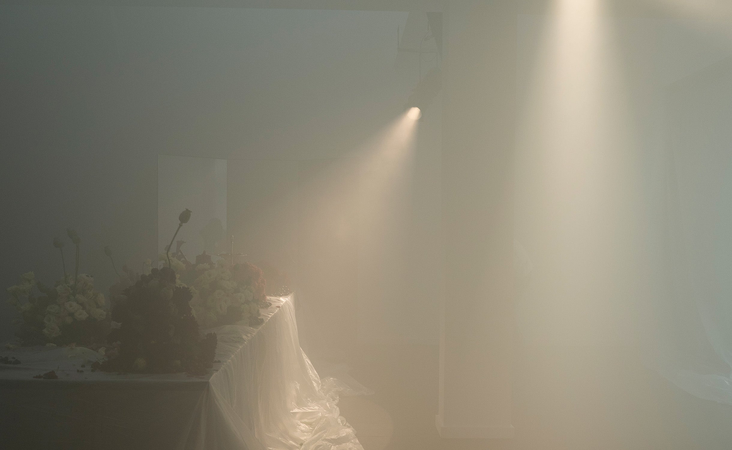 Flower-filled installation illuminated through scented haze at ioannes A Salon.