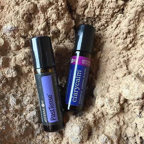 Two essential oil roller bottles on textured sandy surface.