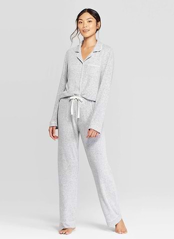 Woman wearing light gray pajama set with button-up top and drawstring pants.
