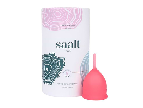 Pink Saalt menstrual cup beside branded cylindrical packaging on a light gray background.