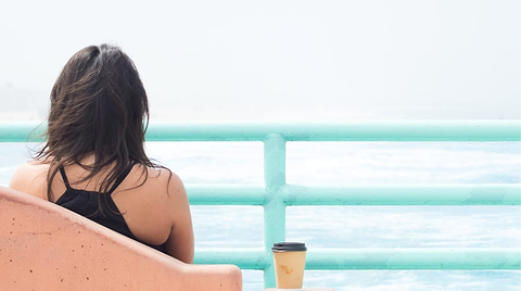 Woman drinking coffee looking at the ocean