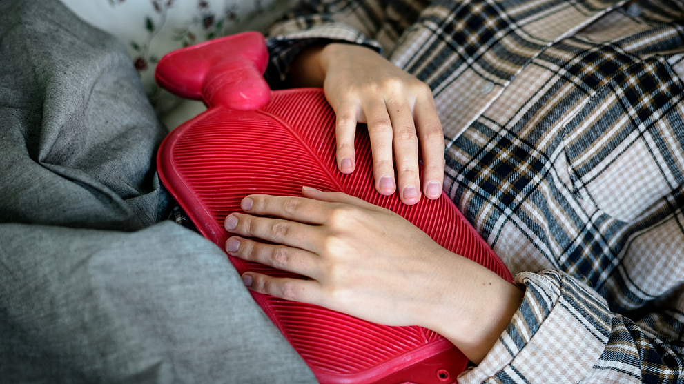 A Girl Using A Heating Pad To Help With First Period Symptoms