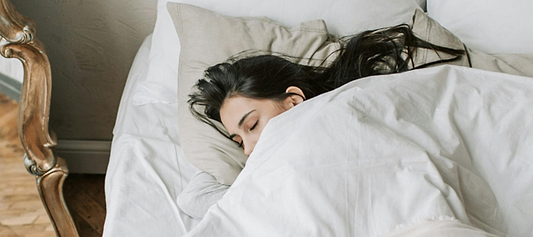 Women sleeping on their side under white bedding, resting on a pillow.