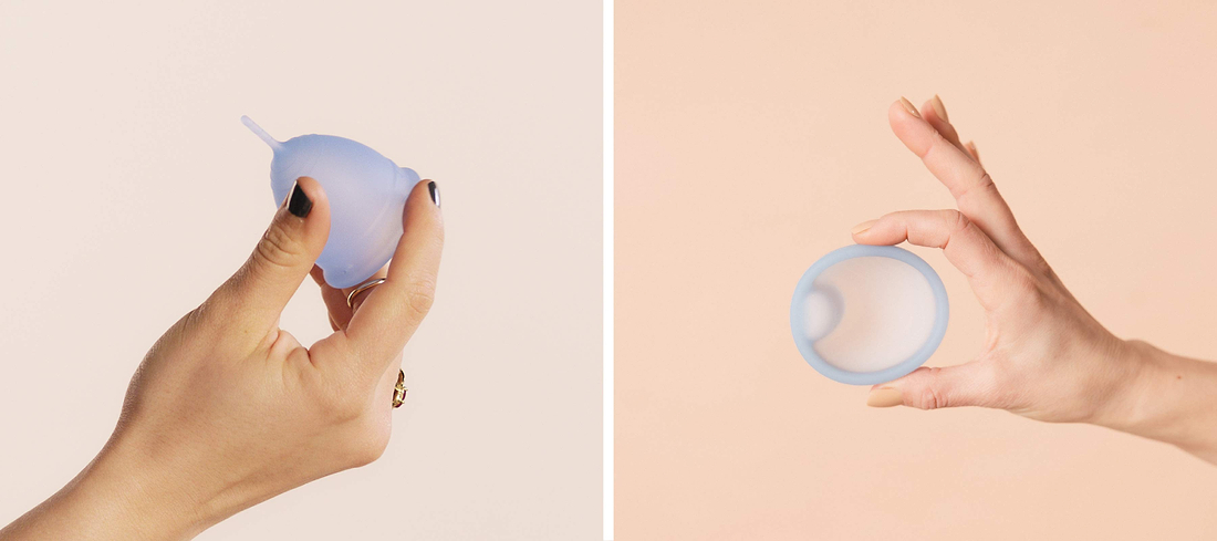 Hands holding a light blue menstrual cup from side and top views against a soft pastel background.