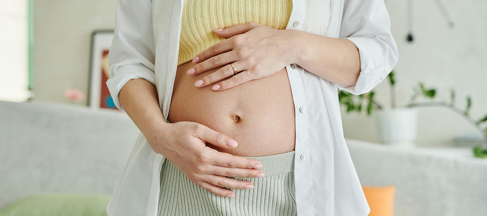 Person gently holding abdomen, suggesting digestive health, body awareness, or pregnancy concept.