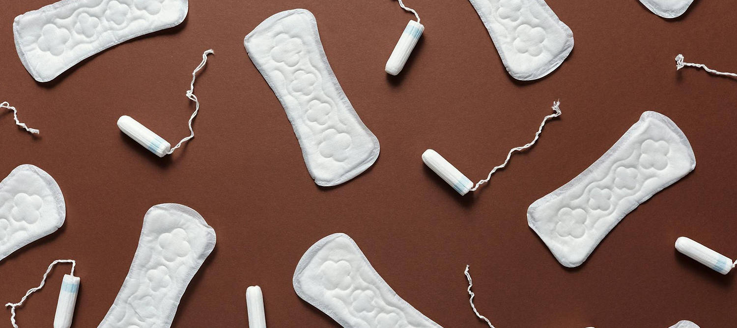 Tampons and sanitary pads arranged in a flat lay pattern on a brown background.