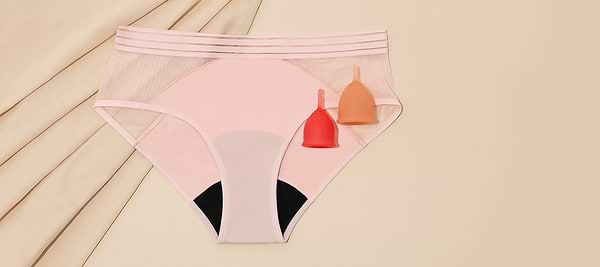 Pink period underwear with two menstrual cups on a beige background.