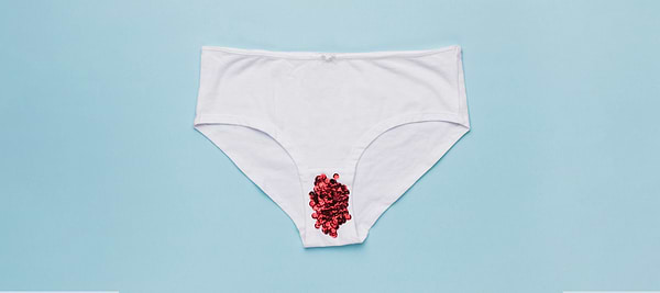 White underwear with red beads placed on the front, against a blue background.