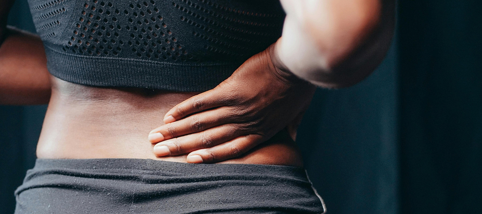 Person in athletic wear holding lower back, suggesting back pain or muscle strain.
