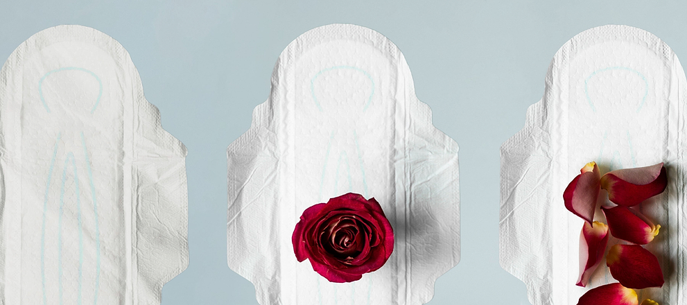 Three sanitary pads displayed with red rose and petals on a light blue background.