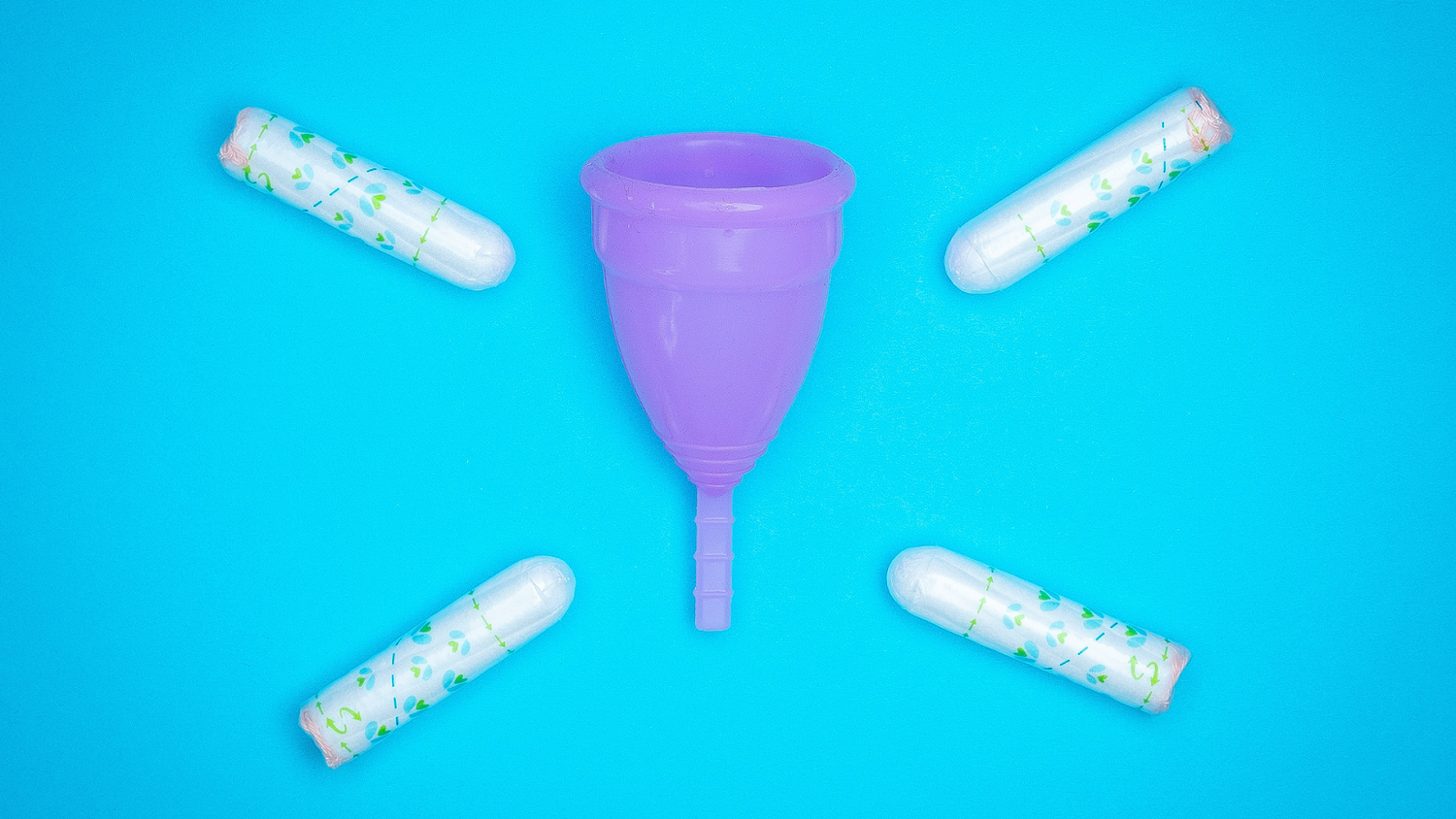 Purple menstrual cups surrounded by tampons