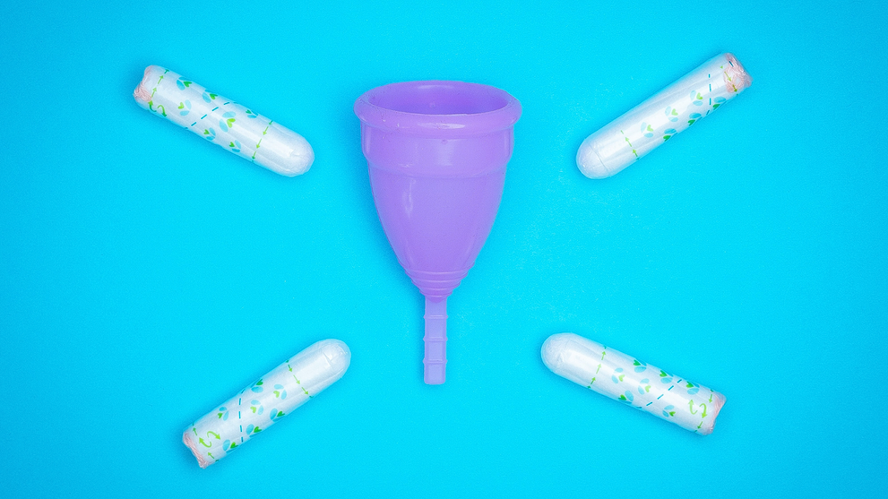 Purple menstrual cups surrounded by tampons