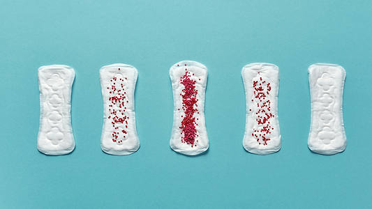 Five sanitary pads on a blue background, illustrating varying menstrual flow levels with red beads.