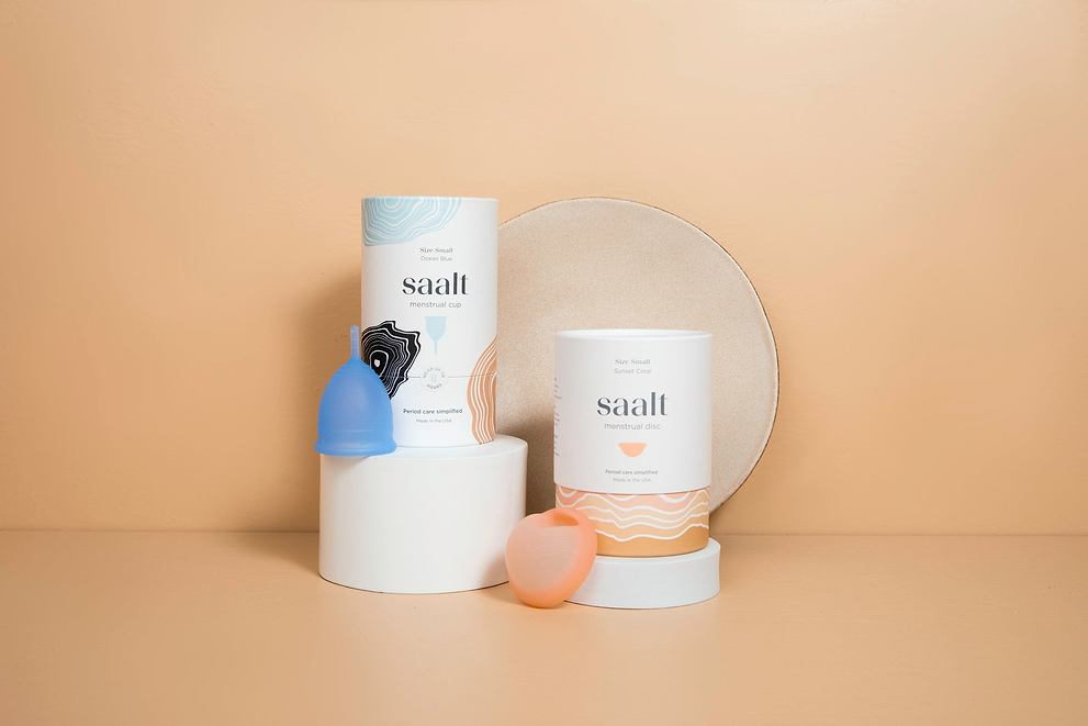 Menstrual cup and disc products displayed with packaging on a neutral peach background