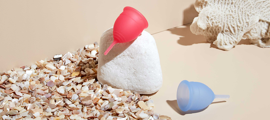 Colorful menstrual cups displayed in a beach-inspired setting, blending comfort, sustainability, and style.