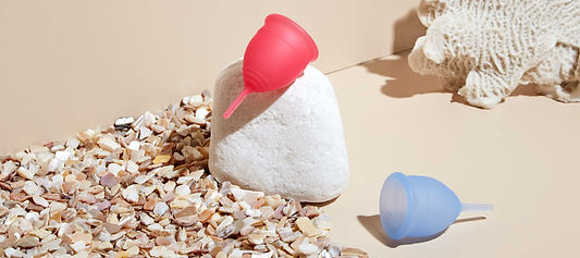 Colorful menstrual cups displayed in a beach-inspired setting, blending comfort, sustainability, and style.