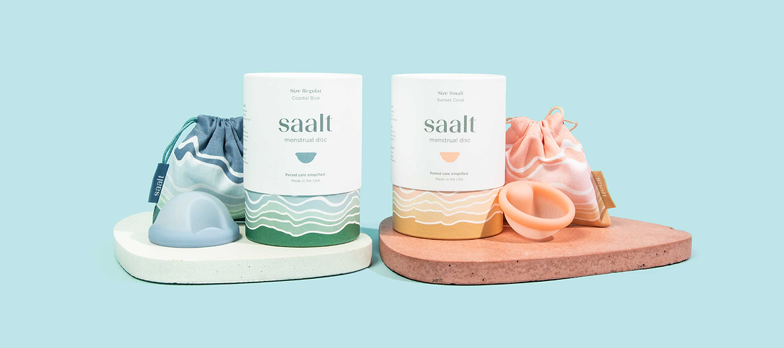 Saalt menstrual disc products with storage pouches and reusable discs displayed on pastel stands.