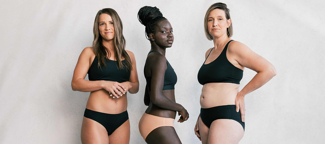 Three women of different body types wearing black underwear and bras, posing confidently against a neutral backdrop.
