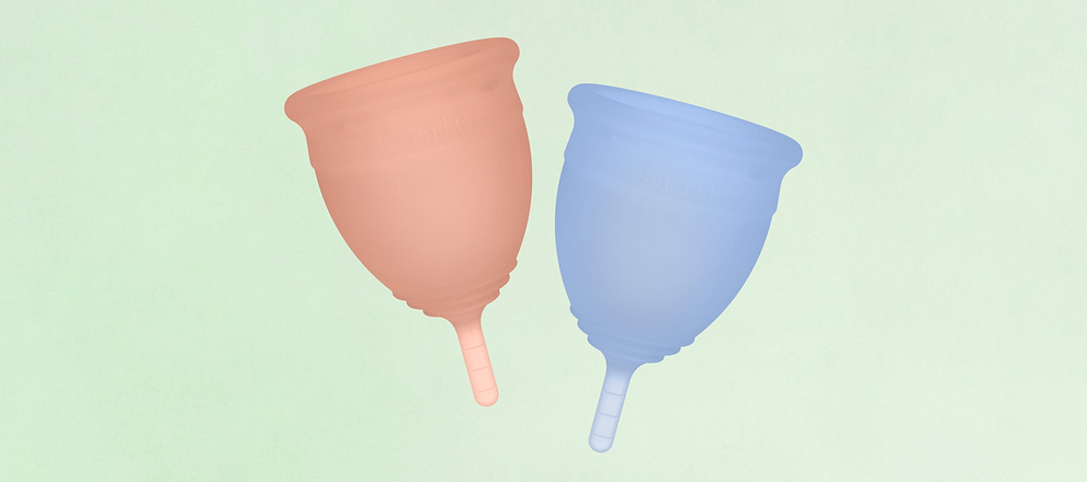Pink and blue menstrual cups displayed side by side on a soft green background.