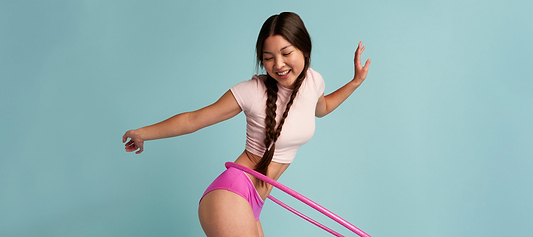 Period pants for teens: smiling teen hula-hooping in bright pink period underwear against a blue background, showing leakproof comfort for school days.