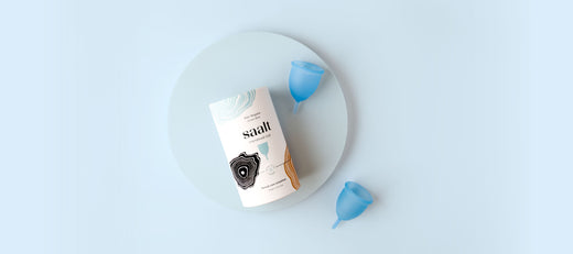 Saalt menstrual cup packaging with two blue cups arranged on a soft pastel blue background.