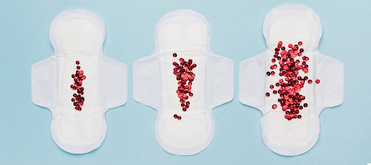 Three sanitary pads with increasing amounts of red beads, illustrating light to heavy flow.