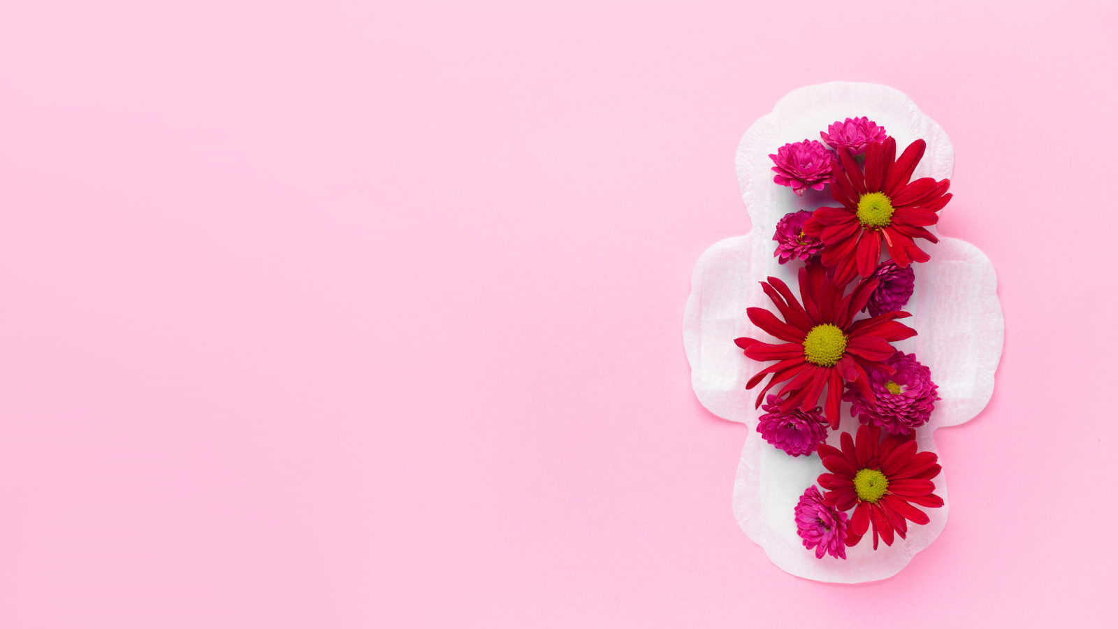 Sanitary pad decorated with red and pink flowers on a pastel pink background.