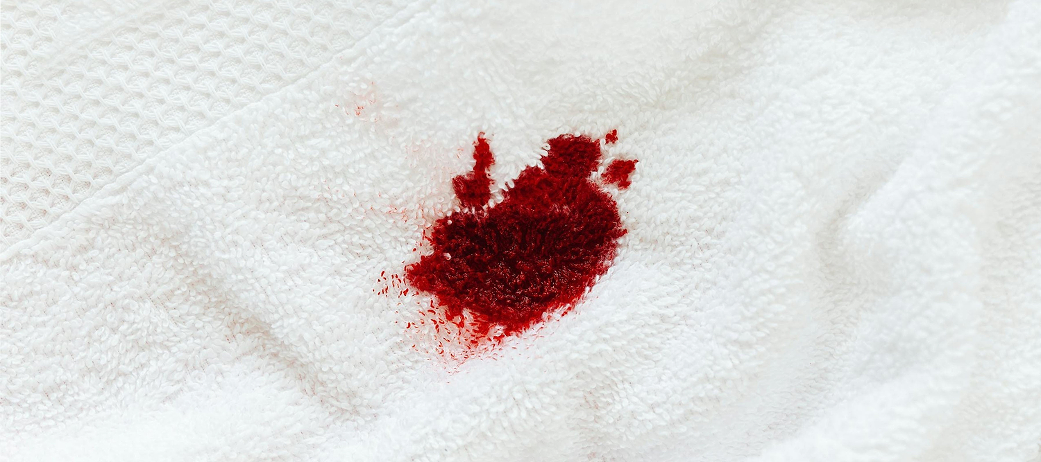 Red stain on a white towel fabric.