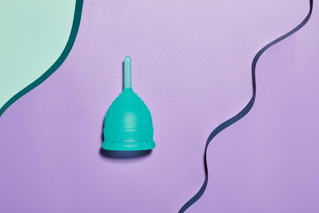 Teal menstrual cup on a purple background with abstract curved shapes.
