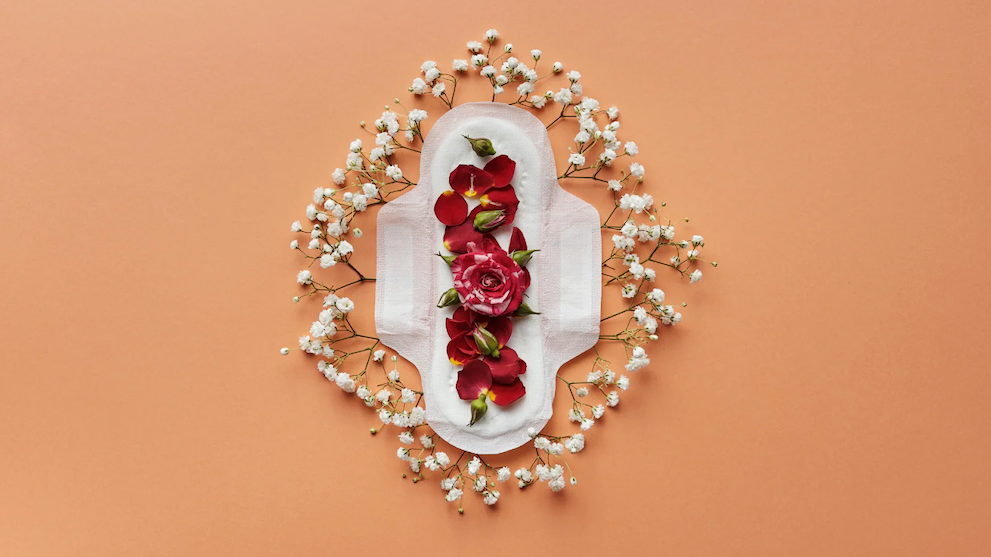 Sanitary pad decorated with red flowers and white blossoms on a peach background, arranged artistically.