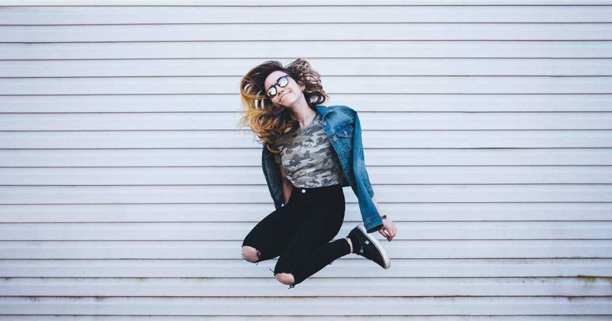 Girl in jean jacket jumping.