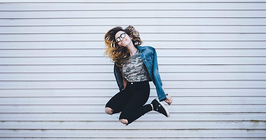 Girl in jean jacket jumping.