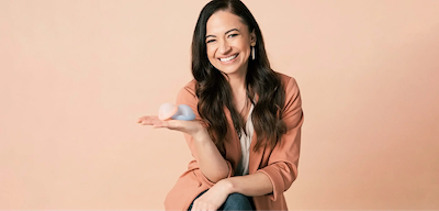 Saalt’s Founder and CEO, Cherie, smiling and holding two Saalt Discs in colors Coastal Blue and Sunset Coral.