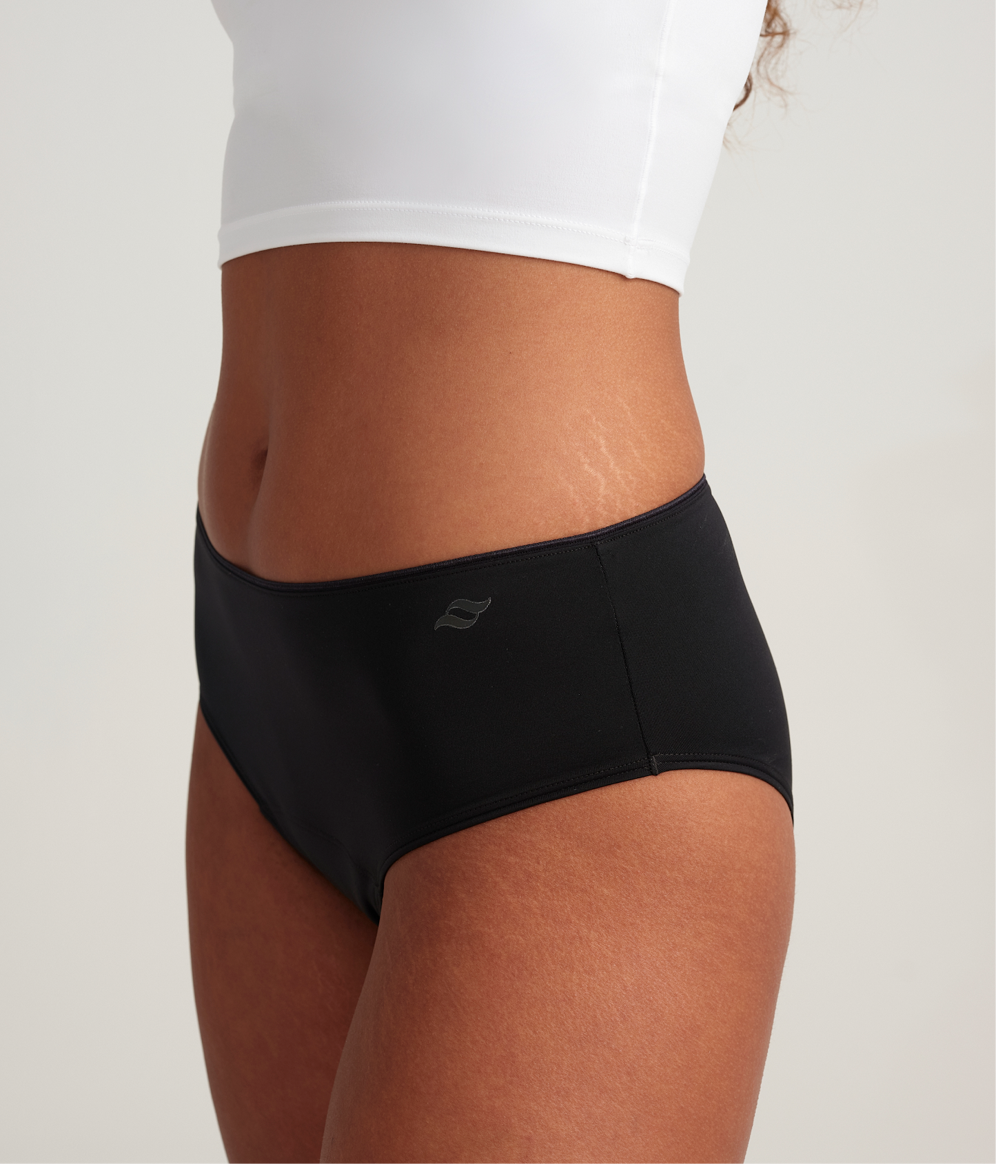 Person wearing black high-waisted swim bottoms on a plain background